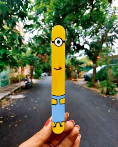 a hand holding up a yellow and blue pencil with a cartoon character on it's end
