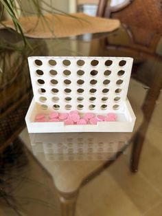 a white basket with pink flowers sitting on top of a table
