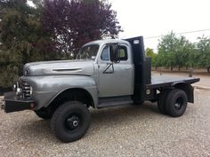 an old gray truck is parked on the gravel
