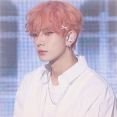 a man with pink hair and ear piercings on his ears, wearing a white shirt
