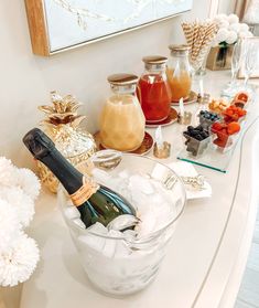 a champagne bottle sitting in a glass bowl filled with ice cubes on top of a counter