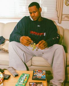 a man sitting on top of a white couch next to a table filled with candy