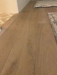 a wooden floor with a rug on top of it next to an open door and window