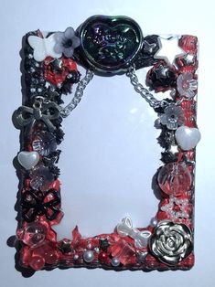 a red and black photo frame with flowers, hearts, and other things attached to it