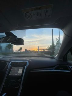 the sun is setting over a city from inside a car, as seen through the windshield