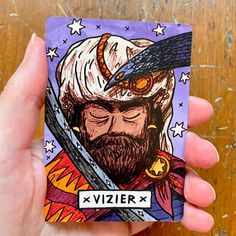 a hand holding up a card with an image of a bearded man wearing a hat