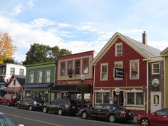 several cars are parked on the street in front of some buildings with shops and businesses