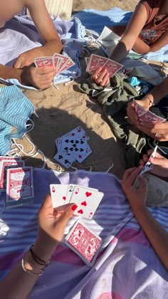 several people sitting on the beach playing cards