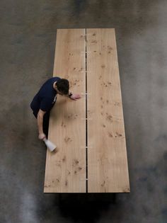 a man standing on top of a wooden table next to a white object in the air