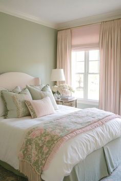 a bedroom with green walls, pink curtains and a white bed in the middle of it