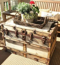 an old trunk sitting on top of a wooden deck next to a potted plant