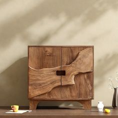 a wooden cabinet sitting on top of a table next to vases and other items