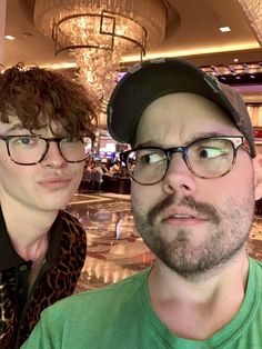 two men are posing for the camera in front of a chandelier at a casino