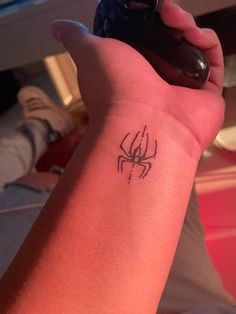 a person with a spider tattoo on their arm holding a remote control in their hand