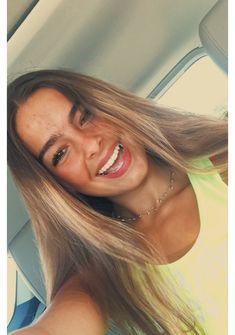 a woman with long hair is smiling in the back seat of a car
