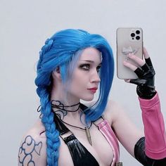 a woman with blue hair is holding up her cell phone to take a selfie