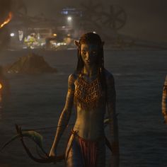 an image of a woman standing in the water holding a bow and arrow with other people around her