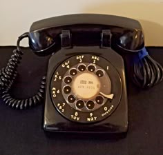 an old fashioned telephone sitting on top of a black table next to a white wall
