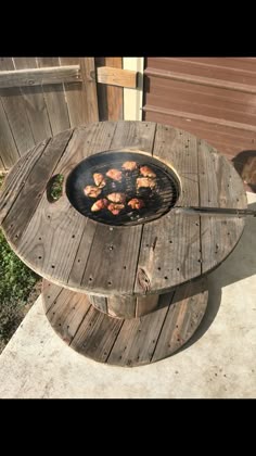 some food is cooking on top of a wooden table with a grill in the middle