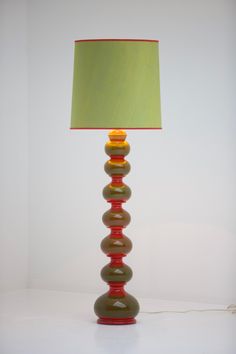 a lamp that is sitting on top of a white surface with a green lampshade