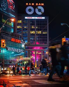 a busy city street at night with people crossing the street