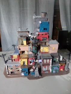 a pile of toy buildings sitting on top of a floor next to a curtained window