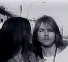 a man with long hair standing next to a woman