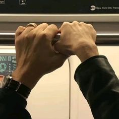 two hands are holding onto the handle of a subway car, while another hand holds on to it