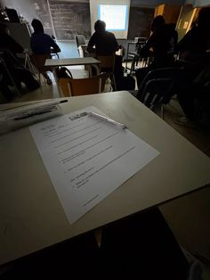 there is a piece of paper on top of the table in front of people sitting at desks