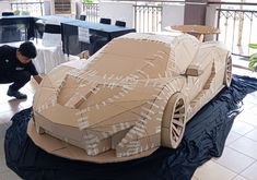 a man working on a cardboard model of a car
