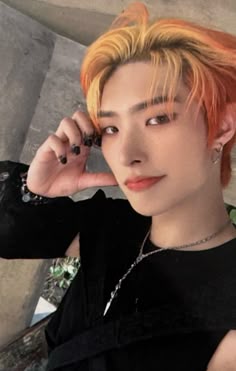 a young man with orange hair and piercings on his ears talking on a cell phone