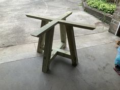 a wooden table sitting on top of a cement floor next to a blue trash can
