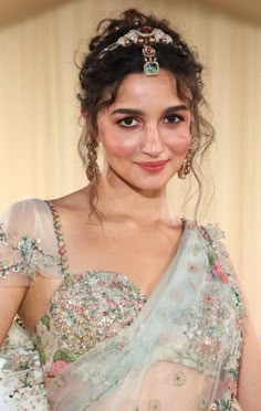 a woman in a dress with flowers on her head and veil over her shoulders, smiling at the camera