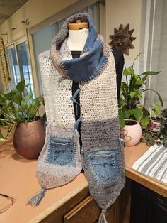 a pair of jeans hanging from a hook on a table next to potted plants
