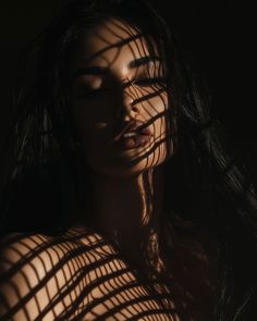 a woman with her eyes closed standing in front of a shadow from the sun on her body