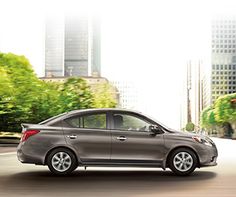 a silver car is driving down the street in front of tall buildings and skyscrapers
