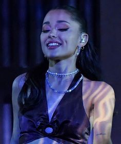 a woman with long hair wearing a black dress and smiling at something in her hand
