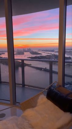 a living room filled with furniture and large windows overlooking the city at sunset or dawn
