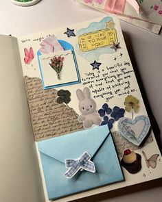 an open book with some cards and decorations on top of the pages, next to a cupcake