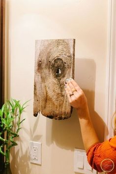 a woman holding up a piece of wood with an eye on it