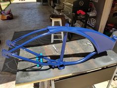 a blue bike frame sitting on top of a metal table