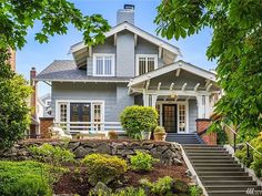 a blue house with steps leading up to the front door and entry way, surrounded by greenery
