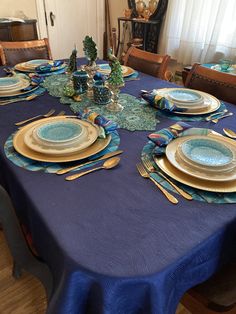 the table is set with blue and gold plates, silverware, and napkins
