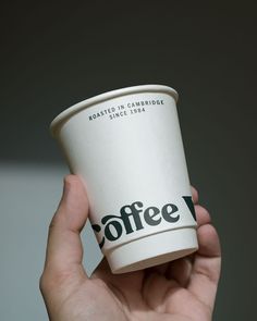 a person holding up a coffee cup in their hand