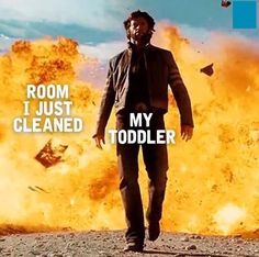 a man in a suit and tie walking through a field with an explosion behind him