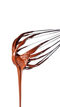 a whisk filled with chocolate on top of a white surface