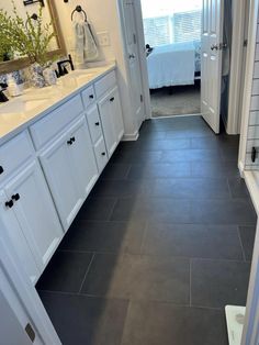 a bathroom with black tile flooring and white cabinets