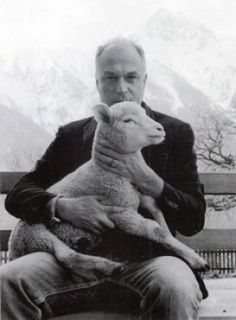 a man sitting on a bench holding a sheep