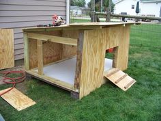 a dog house built into the grass in front of a house with tools on it