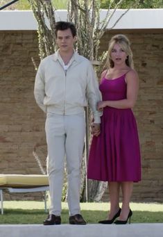 a woman in a pink dress standing next to a man in a white shirt and tie